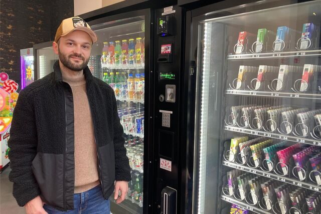Ein Mann steht in einem Kiosk vor mehreren Automaten.