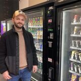 Ein Mann steht in einem Kiosk vor mehreren Automaten.