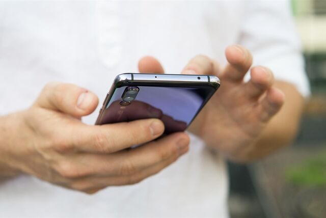 Eine junge Frau hält ein Smartphone in der Hand.