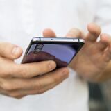 Eine junge Frau hält ein Smartphone in der Hand.