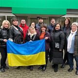 Ukrainerinnen und Ukrainer stehen vor dem Redaktionsgebäude in Marl. Drei von ihnen halten die Landesflagge in die Kamera.