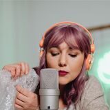 frau nimmt einen asmr podcast auf und knistert dafür mit folie vor einem mikrofon