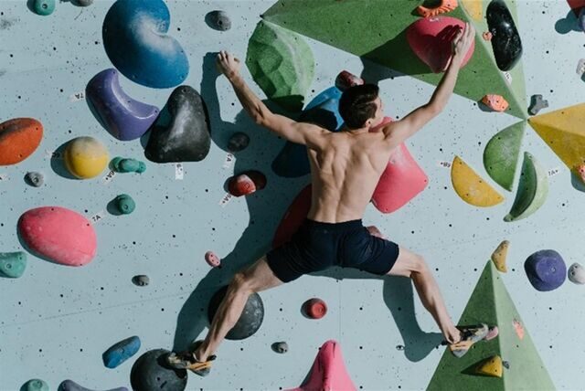 mann klettert an einer boulderwand