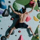 mann klettert an einer boulderwand