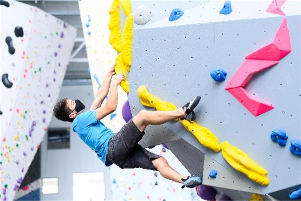 mann klettert eine boulderwand hoch mann klettert eine boulderwand hoch