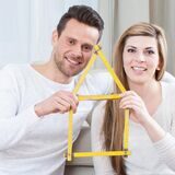 Ein Mann und eine Frau haben aus einen Zollstock in Haus-Form geknickt.