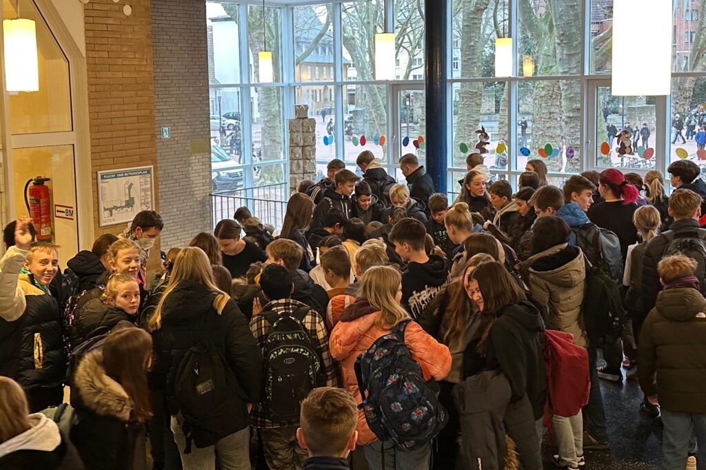 Viele Kinder stehen im ASG vor einem Stand mit Kuchen Viele Kinder stehen im ASG vor einem Stand mit Kuchen