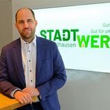 Im Vordergrund steht Stadtwerke-Geschäftsführer Oliver Kleine, im Hintergrund ist das Logo der Stadtwerke zu erkennen.