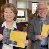 Eine Frau und ein Mann halten Prospekte in der Hand.