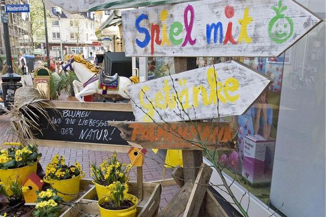 Bunte Schilder und Blumen für den Frühlingsmarkt stehen vor einem Schaufenster in Castrop-Rauxel.