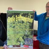 Die Hembrauker Peter Teßartz und Dennis Röhl präsentieren das große Plakat zur geplanten Eröffnung der Museumswiese Hembrauk am 3. Juni 2023.