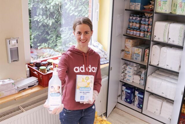 Ralitsa Anastasova steht bei der Recklinghäuser Tafel vor einem Schrank und hält Babyartikel in der Hand