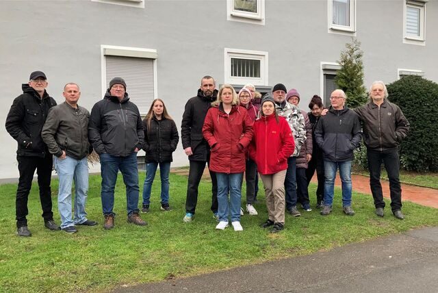 Mieter stehen auf einer Wiese vor einem Mehrfamilienhaus.