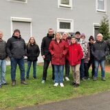 Mieter stehen auf einer Wiese vor einem Mehrfamilienhaus.