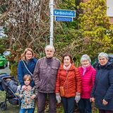 Anwohner stehen unter einem Straßenschild.