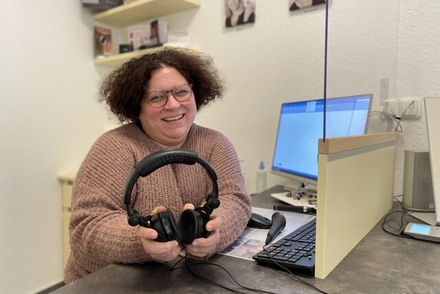 Patricia Schmidt ist Hörakustikerin. Sie sitzt in der Kabine für Hörtests und hält Kopfhörer in der Hand.