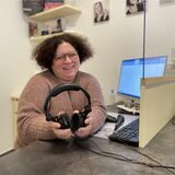 Patricia Schmidt ist Hörakustikerin. Sie sitzt in der Kabine für Hörtests und hält Kopfhörer in der Hand.