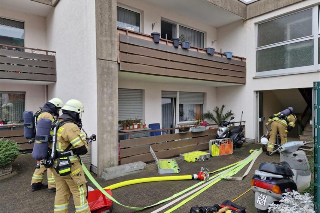 Drei Feuerwehrleute mit Atemschutzgerät hantieren mit Schläuchen vor den Balkonen eines Mehrfamilienhauses in Recklinghausen. Drei Feuerwehrleute mit Atemschutzgerät hantieren mit Schläuchen vor den Balkonen eines Mehrfamilienhauses in Recklinghausen.