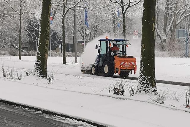 Schnee wird von einem Gehweg geräumt.