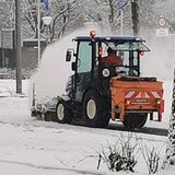 Schnee wird von einem Gehweg geräumt.