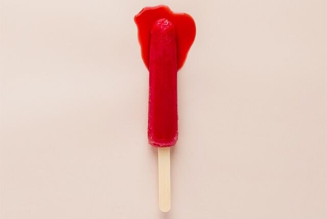 Ein stilisierter Tampon liegt mit roter Farbe getränkt auf beigem Grund.