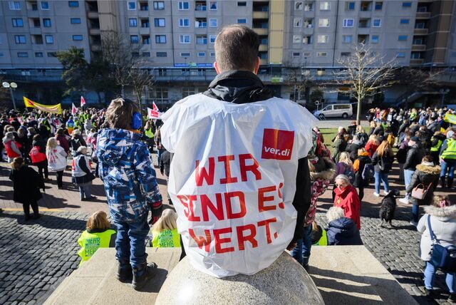 Ein Erzieher in Verdie-Weste und ein Kindergarten-Kind bei einem Warnstreik.
