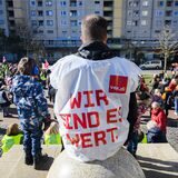 Ein Erzieher in Verdie-Weste und ein Kindergarten-Kind bei einem Warnstreik.