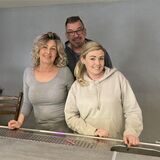 Zwei Frauen und ein Mann stehen hinter eine Kneipentheke.