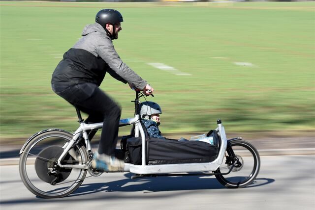 Ein Mann fährt mit seinem Sohn mit einem Elektro-Lastenrad.