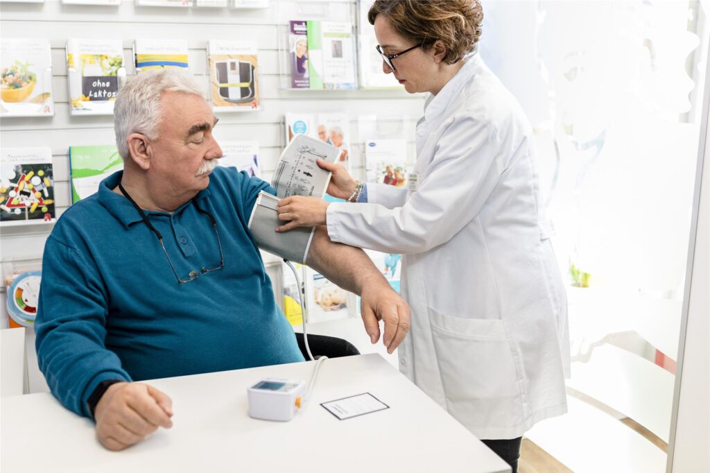 Eine Apothekerin misst bei einem Mann den Blutdruck. Eine Apothekerin misst bei einem Mann den Blutdruck.