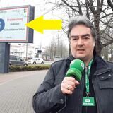 Ein Reporter mit einem Mikrofon in der Hand steht an einer Kreuzung.