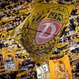 Fans von Dynamo Dresden schwenken eine Fahne.