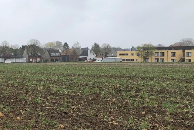 Ein Acker, dahinter das Altenheim Kahrstege und eine Wohnhausreihe