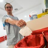 Ein Pfleger hält in einem Krankenhaus in Recklinghausen eine FFP2-Maske über einen Mülleimer.