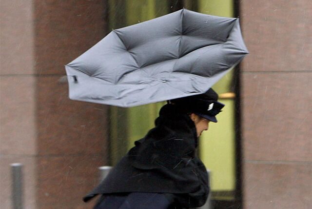 Eine Frau kämpft im Sturm mit ihrem Regenschirm. (Symbolbild)