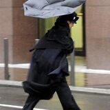 Eine Frau kämpft im Sturm mit ihrem Regenschirm. (Symbolbild)