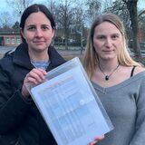 Eva Prost (links) und Saskia Schoof zeigen die lange Liste mit eingeschränkten Betreuungszeiten an der Kita „Schatzkiste“ in Opherdicke. Die beiden Mütter berichten von einer massiven Belastung.