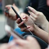Eine Person hat ein Handy in der Hand und tippt darauf herum.
