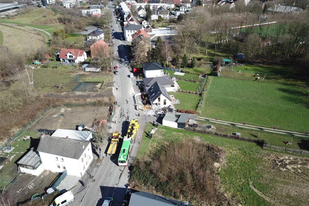 Der Bus ist auf dem Abschleppwagen aufgeladen. Sie stehen bereit zur Abfahrt nach Recklinghausen. Das Haus steht noch, ist aber schwer beschädigt.