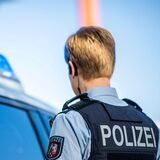 Eine Polizistin steht vor einem Streifenwagen (Symbolbild).