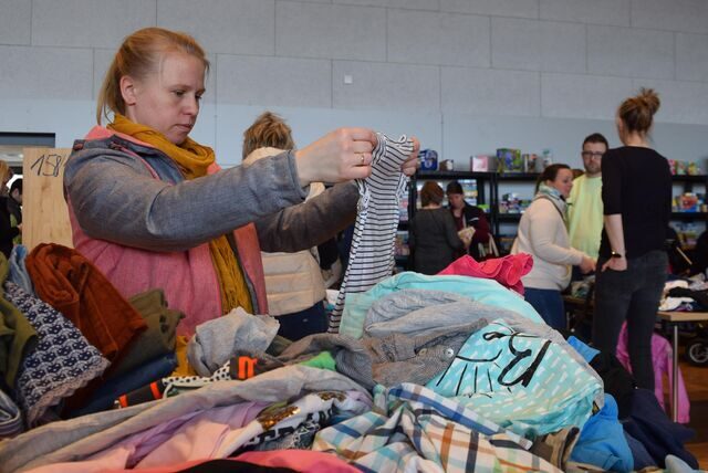 Eine Frau sucht bei einem Flohmarkt nach Kleidung für ihre Kinder.