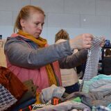 Eine Frau sucht bei einem Flohmarkt nach Kleidung für ihre Kinder.