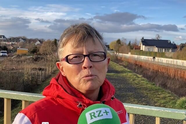 Monika Jacob aus Recklinghausen steht oberhalb des Hellbachs vor einem Tor, das zu einem Betriebsweg der Emschergenossenschaft führt.