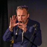 Moderator Helmut Sanftenschneider spricht in ein Mikrofon.