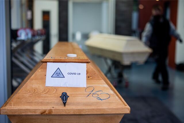 Ein Sarg mit einem Verstorbenen mit der Aufschrift «Covid 19» und dem Zeichen «Biohazard» wird von einem Bestatter in ein Krematorium eingeliefert.