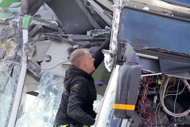 Der Mitarbeiter des Abschleppdienstes befreit lose Teile aus dem Bus-Wrack.