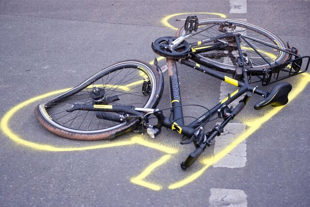 Zu sehen ist ein demoliertes, auf der Straße liegendes Fahrrad, dessen Umriss mit Kreide markiert worden ist.