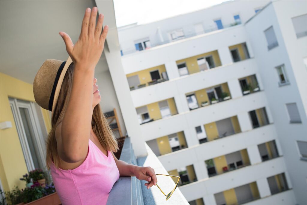 Eine Frau steht auf einem Balkon in einem Wohnblock. Eine Frau steht auf einem Balkon in einem Wohnblock.