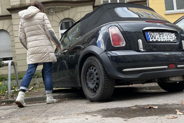 Eine Frau nähert sich einem Auto, das in der Liebigstraße mit den Vorderreifen auf einer Grünfläche steht und den Hinterreifen in der eingezeichneten Parkbox.