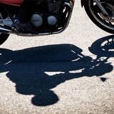 Ein Motorradfahrer und seine Maschine werfen Schatten auf den Asphalt.